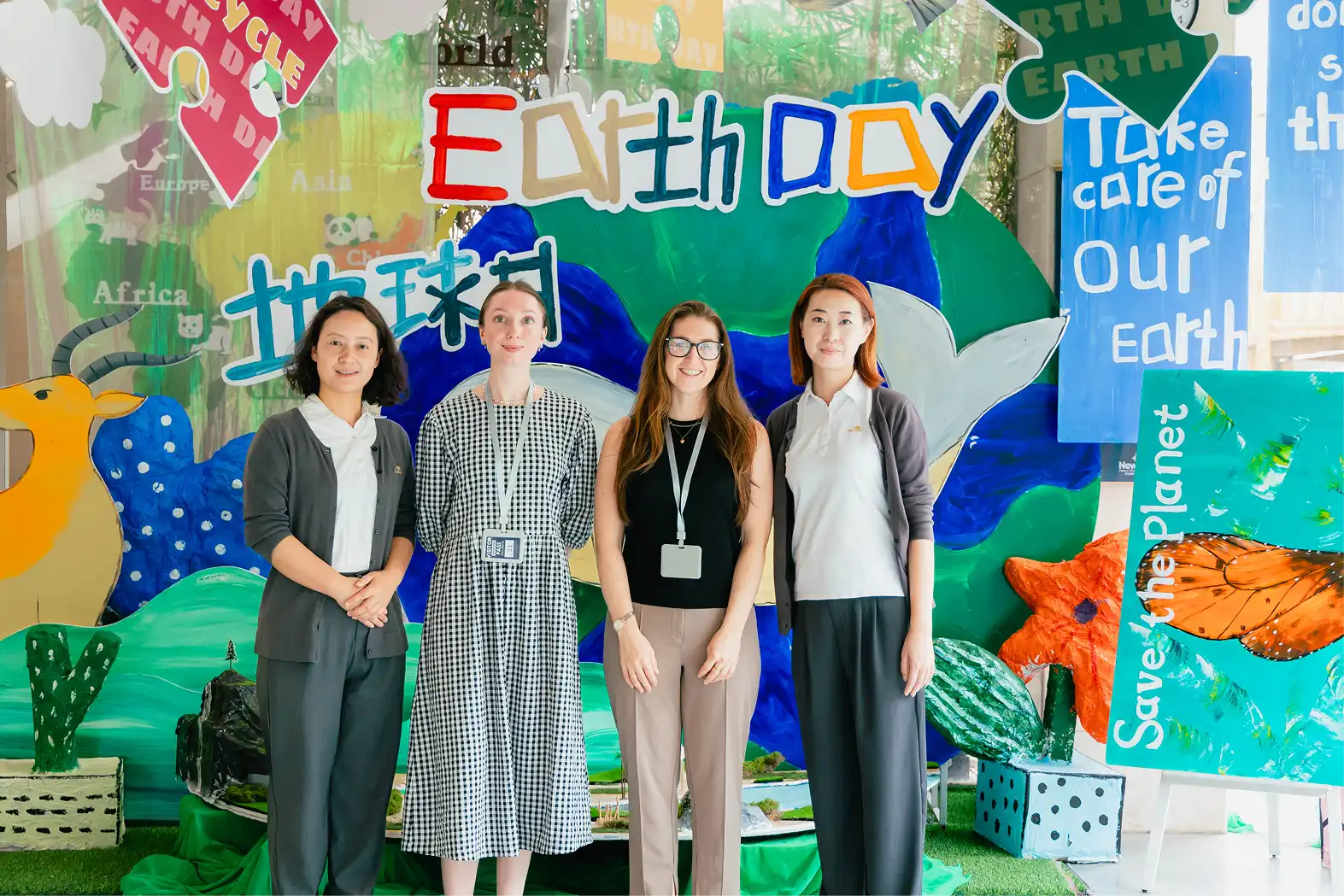 Four members of the Totally Teach team in front of an Earth Day mural at a school